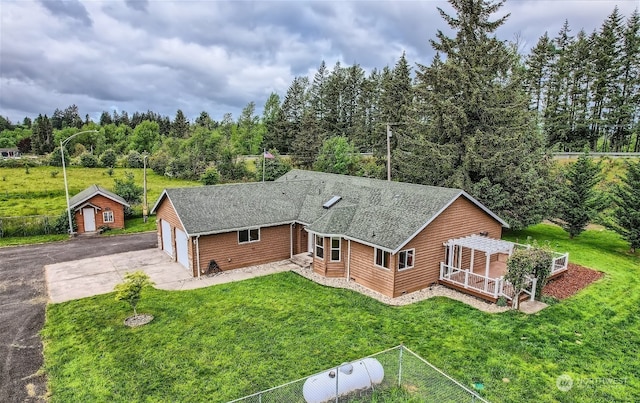 exterior space featuring roof with shingles, fence, driveway, a front yard, and a garage