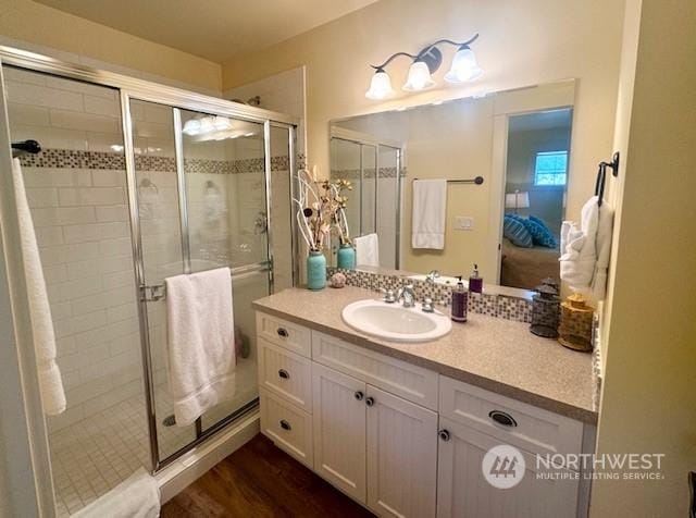 bathroom with hardwood / wood-style flooring, vanity, and a shower with door