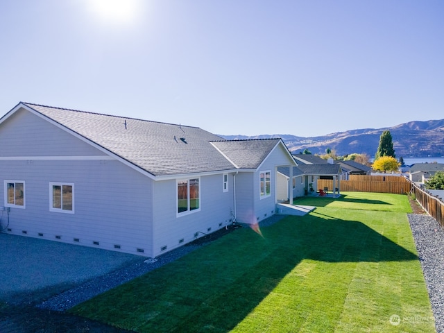 rear view of house with a yard, a mountain view, and a patio area