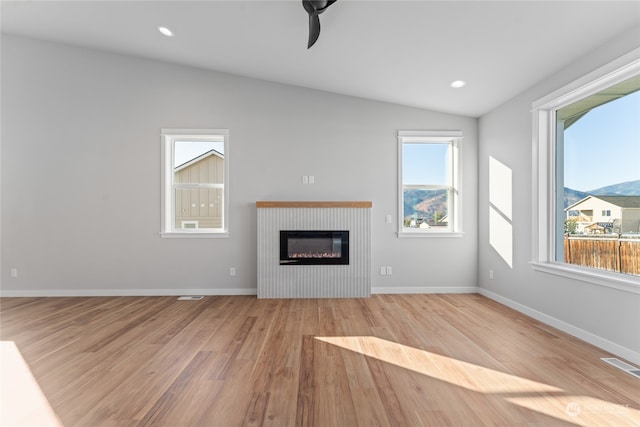 unfurnished living room featuring lofted ceiling, a mountain view, and light hardwood / wood-style floors