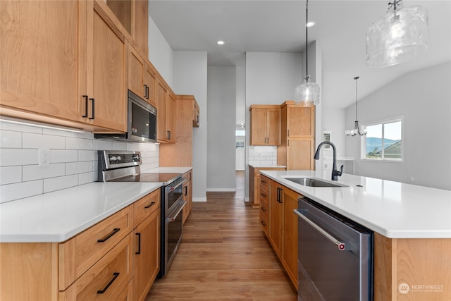 kitchen featuring sink, light wood-type flooring, an island with sink, hanging light fixtures, and stainless steel appliances