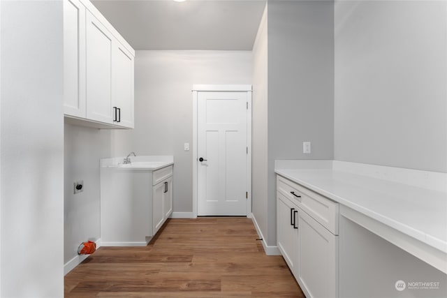 laundry area featuring cabinets, sink, light wood-type flooring, and electric dryer hookup