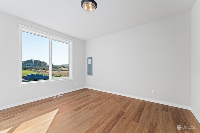 unfurnished room featuring electric panel and wood-type flooring