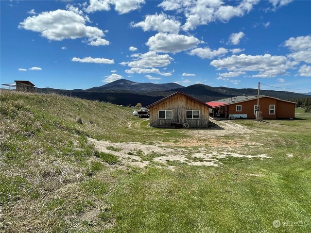 rear view of property featuring a mountain view and a lawn