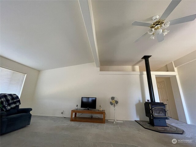 living room with a wood stove, vaulted ceiling with beams, carpet, and ceiling fan