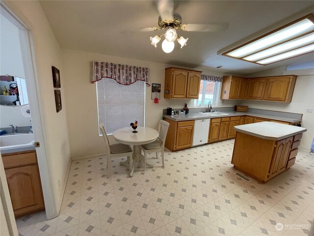 kitchen with ceiling fan, sink, white dishwasher, a kitchen island, and light tile patterned floors