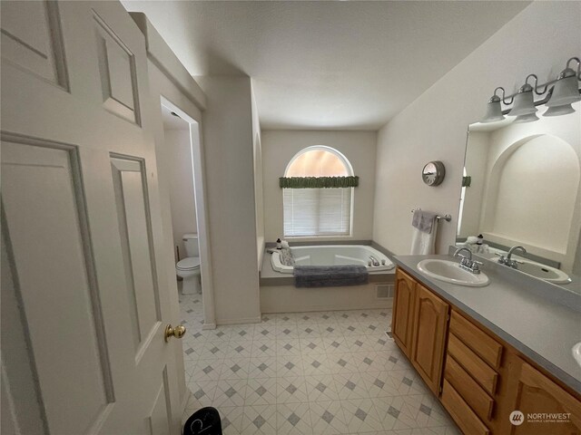 bathroom with double sink vanity, tile patterned floors, toilet, and a tub