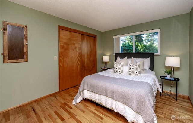 bedroom featuring a closet, a textured ceiling, and light wood-type flooring