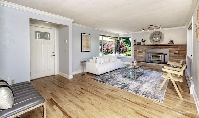 living room featuring track lighting, light hardwood / wood-style floors, crown molding, a textured ceiling, and a baseboard heating unit