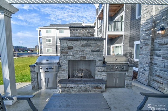 view of patio featuring grilling area, a balcony, and an outdoor stone fireplace