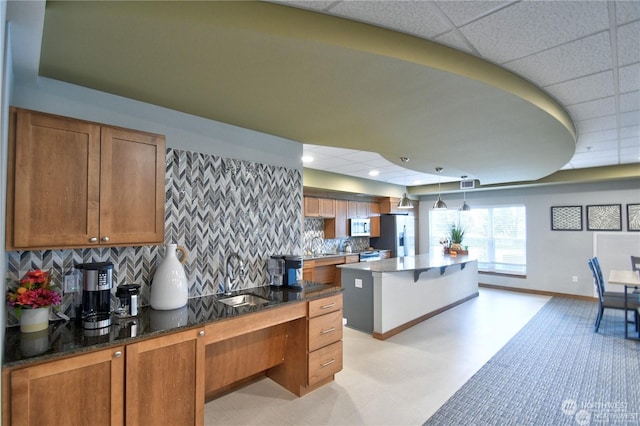 kitchen featuring pendant lighting, sink, stainless steel refrigerator with ice dispenser, and tasteful backsplash