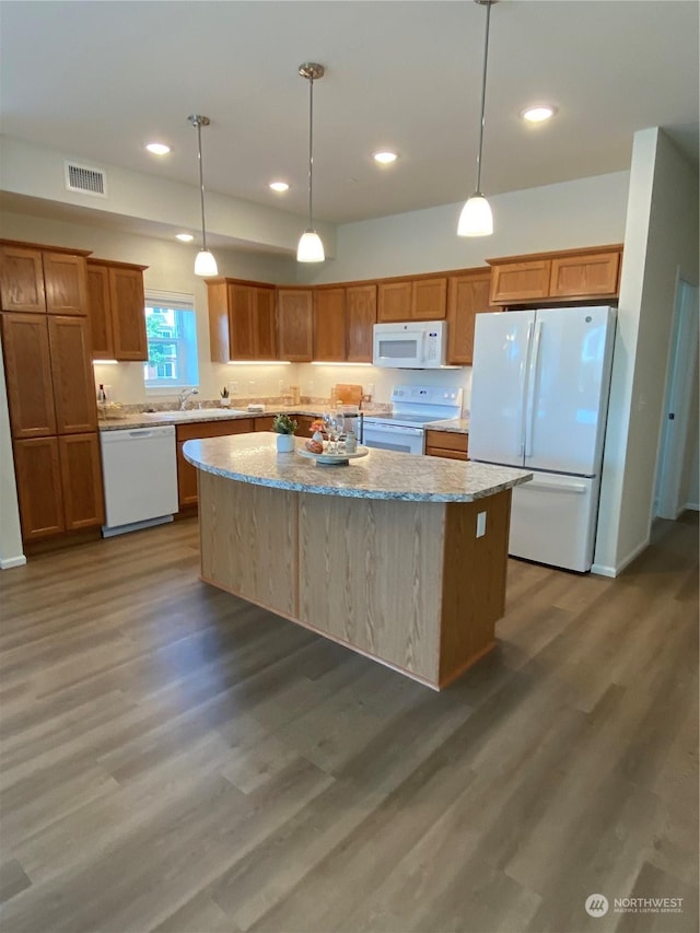 kitchen featuring white appliances, a center island, hanging light fixtures, and dark wood-type flooring