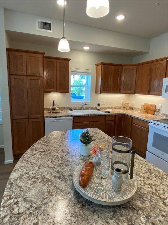 kitchen featuring light stone countertops, white appliances, sink, pendant lighting, and dark hardwood / wood-style floors