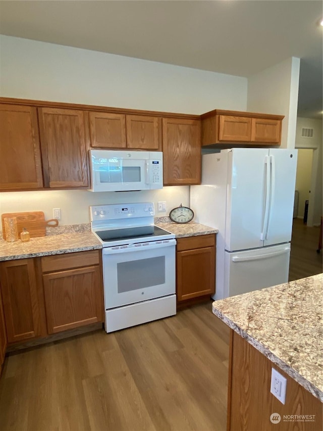 kitchen featuring light stone countertops, white appliances, and light hardwood / wood-style floors