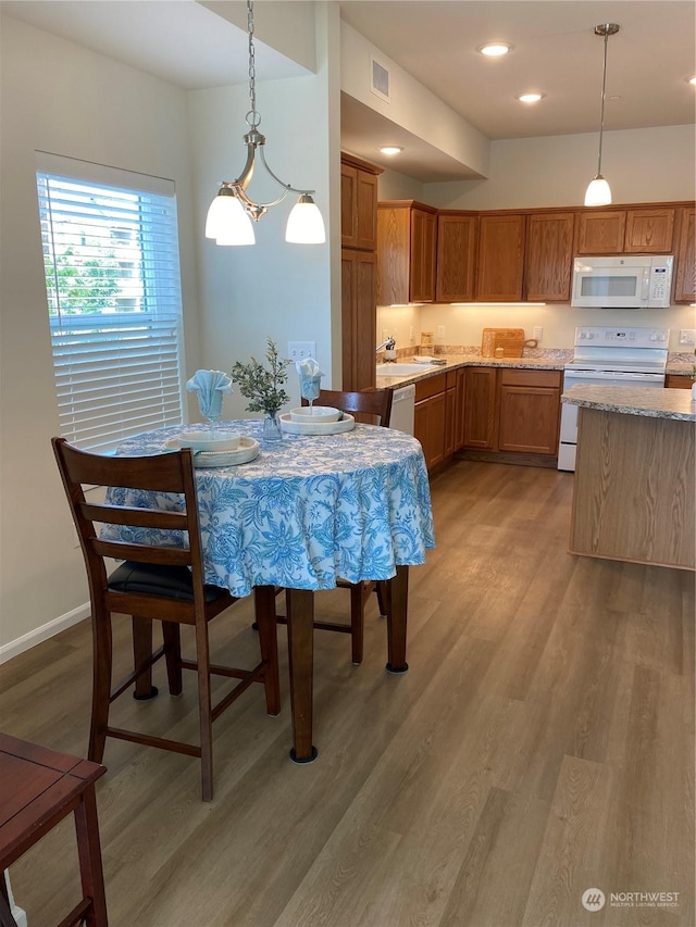 dining area featuring wood-type flooring, sink, and a chandelier