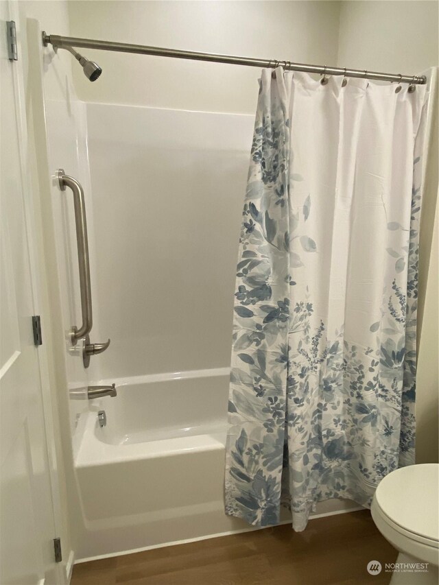 bathroom featuring wood-type flooring, toilet, and shower / bath combo with shower curtain