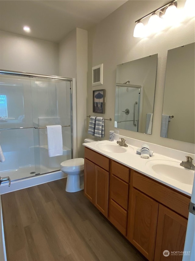 bathroom featuring toilet, a shower with door, vanity, and hardwood / wood-style flooring