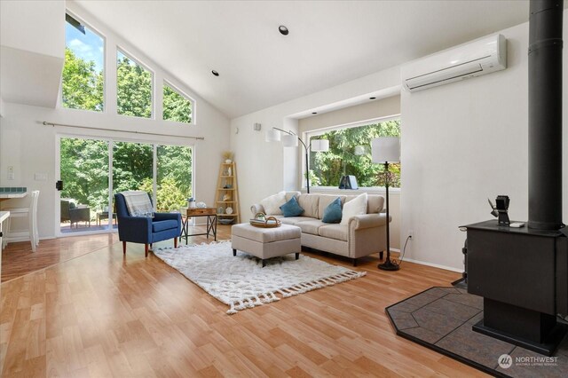 living room featuring high vaulted ceiling, hardwood / wood-style flooring, a wall unit AC, and a wood stove