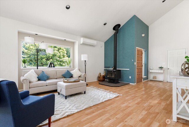 living room with hardwood / wood-style flooring, an AC wall unit, a wood stove, and high vaulted ceiling