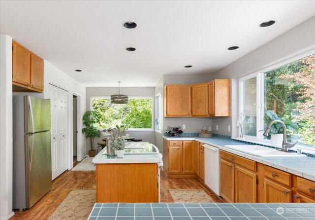 kitchen featuring stainless steel refrigerator, tile countertops, a kitchen island, and white dishwasher