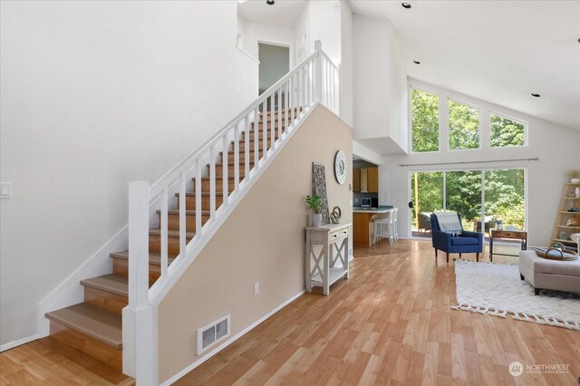 living room with high vaulted ceiling and light hardwood / wood-style flooring