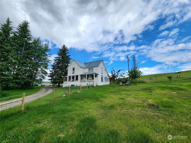 exterior space featuring a rural view, a lawn, and a porch