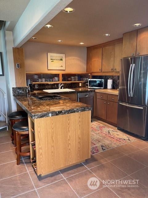 kitchen with dark stone countertops, kitchen peninsula, tile patterned flooring, and black appliances