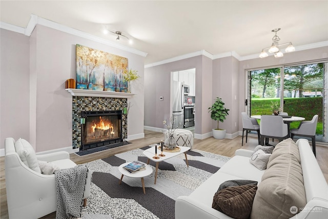 living room with a tile fireplace, crown molding, a notable chandelier, and light wood-type flooring