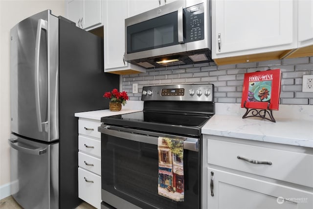 kitchen featuring white cabinetry, stainless steel appliances, light stone counters, and tasteful backsplash