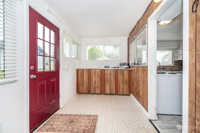 doorway to outside featuring washer / clothes dryer, wooden walls, and plenty of natural light