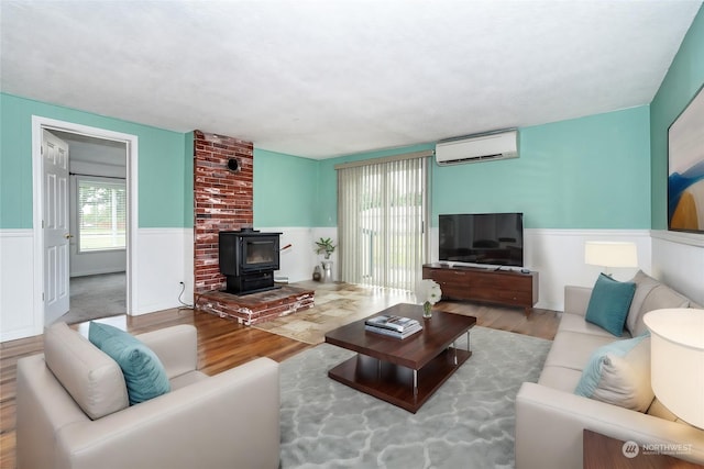 living room with a wood stove, light hardwood / wood-style flooring, and a wall unit AC