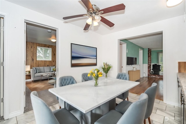 dining room with wooden walls and ceiling fan