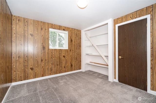 unfurnished bedroom with carpet flooring and wood walls