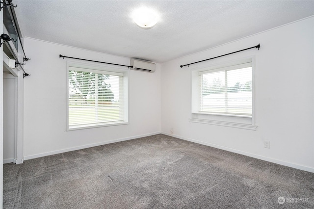 empty room featuring carpet flooring, a textured ceiling, and a wall mounted AC