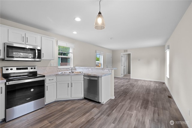 kitchen featuring pendant lighting, appliances with stainless steel finishes, white cabinetry, dark hardwood / wood-style floors, and kitchen peninsula