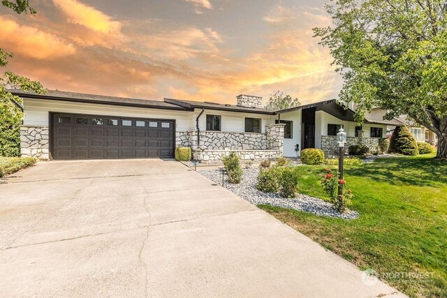 ranch-style house featuring a garage and a yard