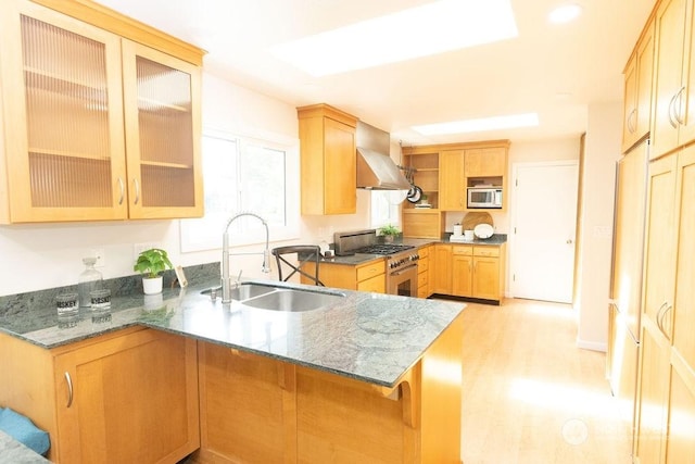 kitchen with sink, stainless steel stove, dark stone countertops, ventilation hood, and kitchen peninsula