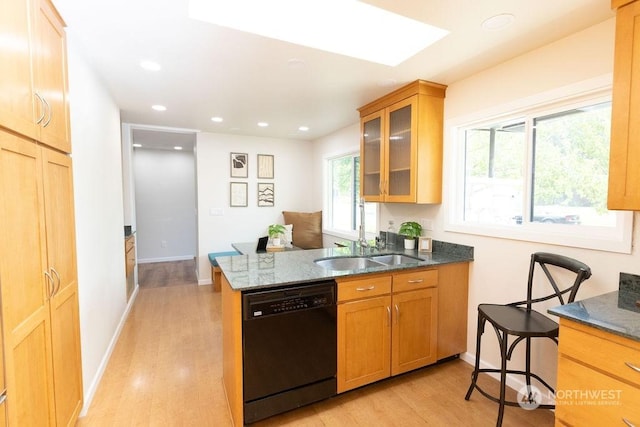 kitchen featuring dishwasher, sink, dark stone counters, kitchen peninsula, and light wood-type flooring