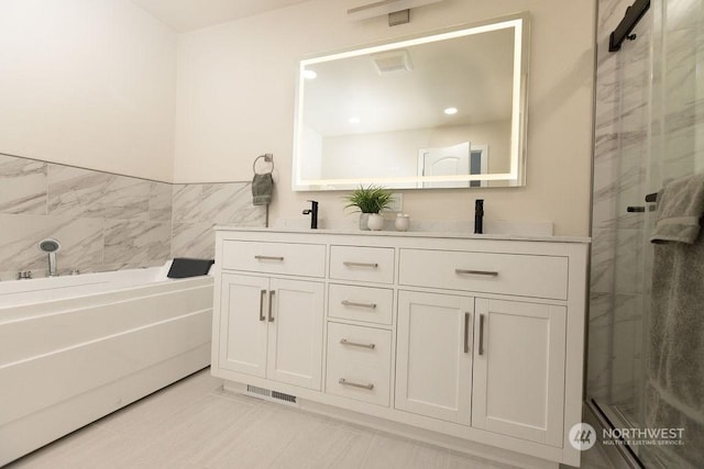 bathroom featuring tile patterned floors, vanity, a shower with shower door, and tile walls