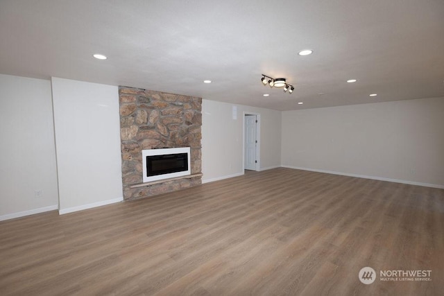 unfurnished living room with a stone fireplace and light hardwood / wood-style flooring