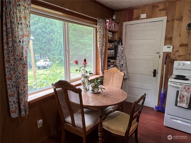 dining space featuring dark hardwood / wood-style floors, a healthy amount of sunlight, and wood walls