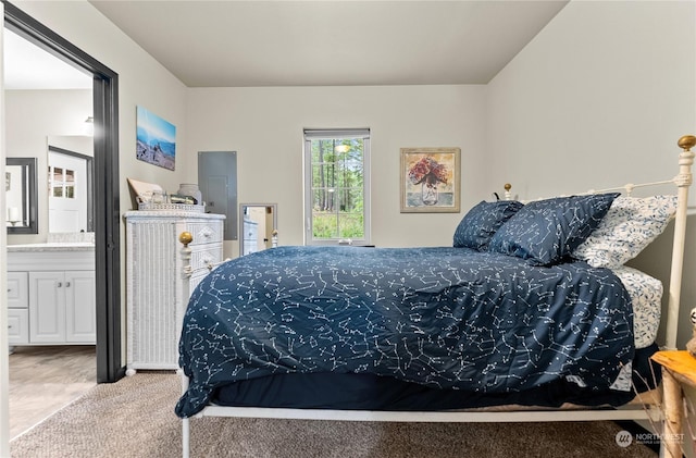 bedroom with ensuite bathroom and light colored carpet