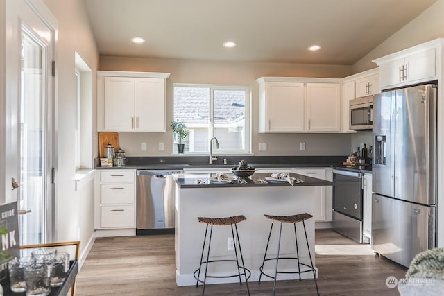 kitchen with dark countertops, white cabinetry, appliances with stainless steel finishes, and a sink