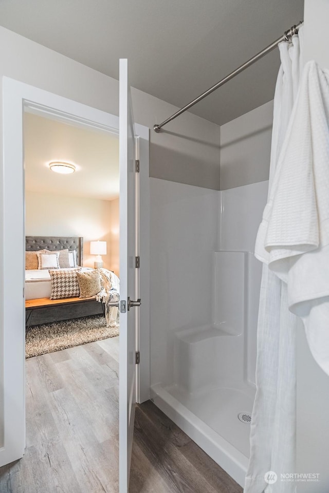 ensuite bathroom with a shower stall, ensuite bath, and wood finished floors