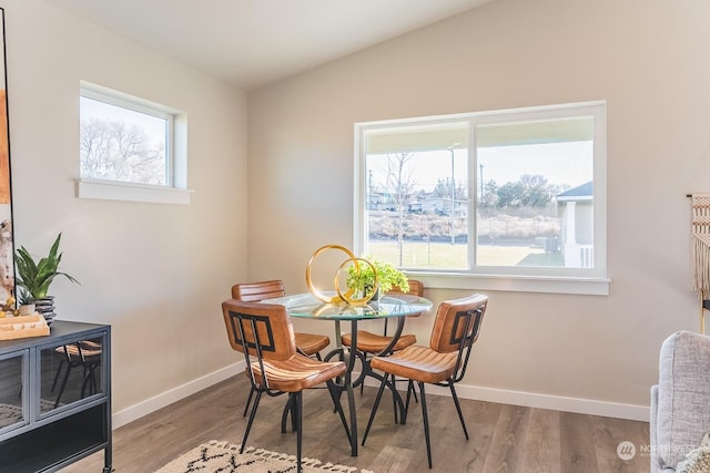 dining area with lofted ceiling, baseboards, and wood finished floors