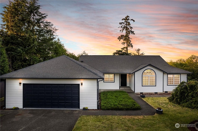 ranch-style home featuring a garage, a shingled roof, a front yard, and aphalt driveway