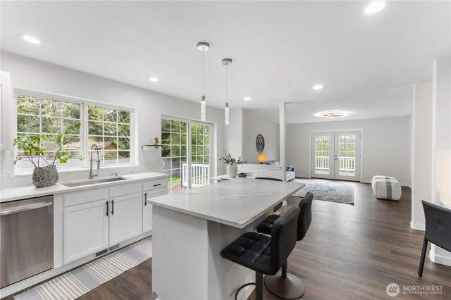 kitchen with a kitchen island, a kitchen bar, stainless steel dishwasher, a sink, and white cabinetry
