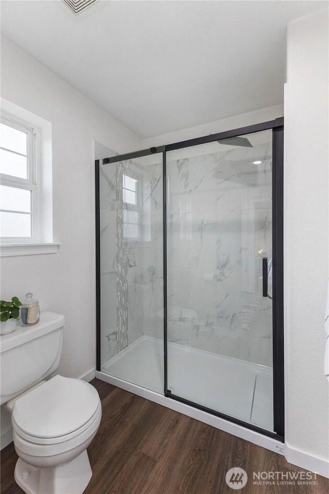 bathroom featuring baseboards, a marble finish shower, wood finished floors, and toilet