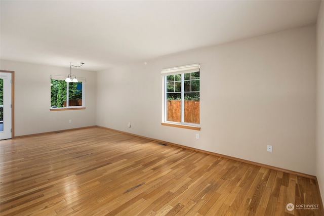 spare room featuring baseboards, visible vents, and light wood-style floors