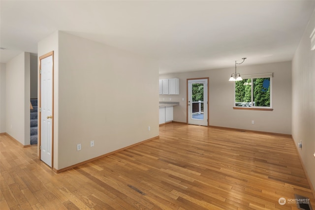 unfurnished living room with stairway, light wood-type flooring, and baseboards